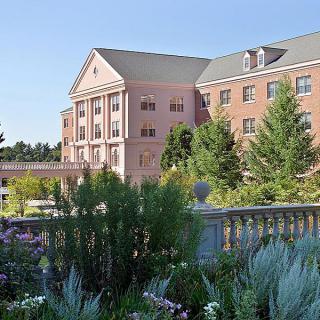 A picturesque view of a building surrounded by lush greenery and gardens.