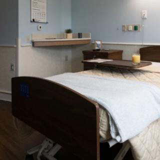 A hospital room with a neatly made bed and medical equipment.