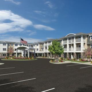 A modern apartment complex with a large parking lot and an American flag flying at the entrance.