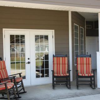 A cozy porch with striped rocking chairs and French doors leading outside.