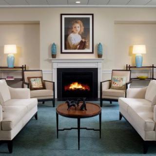 A well-decorated living room featuring a central fireplace and artwork, flanked by sofas and lamps.