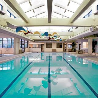 A spacious indoor swimming pool with a skylight roof, perfect for leisure and exercise.