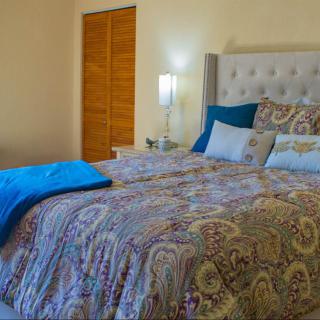 A cozy bedroom featuring a neatly made bed with patterned bedding, pillows, and a lamp on the nightstand.