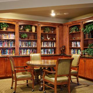 A cozy library corner with wooden bookshelves, a round table, and chairs for reading.