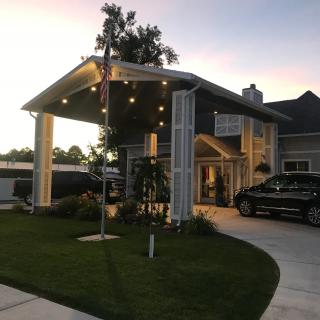 A house with a covered entrance and cars parked in the driveway at dusk.