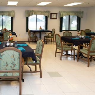 A well-furnished dining area with tables and chairs, featuring natural light from the windows.