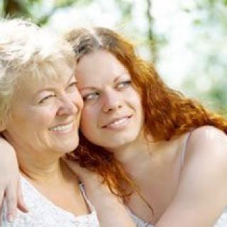 A mother and daughter sharing a warm embrace outdoors.