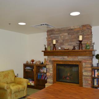 A cozy living room with a stone fireplace, bookshelves, and a comfortable armchair.