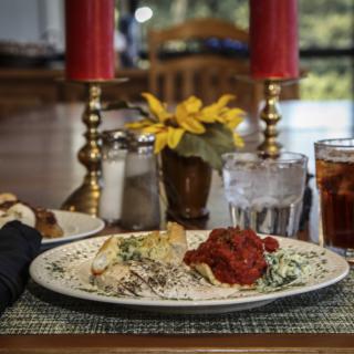 A cozy dinner setup with a plate of pasta, candles, and drinks.