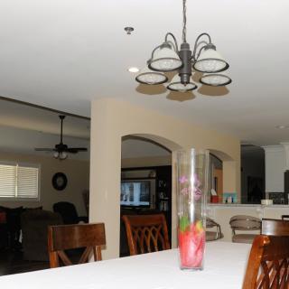 An open-plan dining and kitchen area with a chandelier and vase centerpiece.