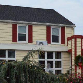 A two-story house with red shutters and yellow siding.