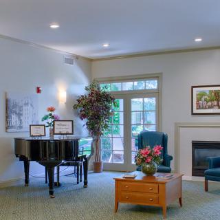 A cozy living room featuring a piano, comfortable seating, and a fireplace.