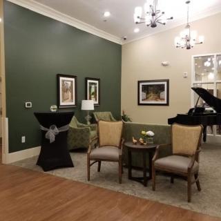 A cozy living room with comfortable seating, a piano, and elegant lighting.