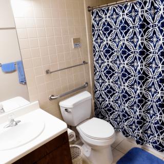 A clean bathroom with a blue geometric shower curtain and modern fixtures.
