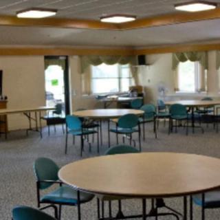 An empty community center room with round tables and chairs arranged for meetings.