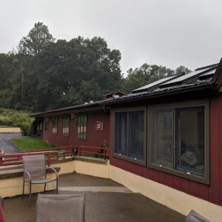 A rainy day view of a red building showcasing large windows and a terrace area.