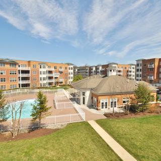 A modern suburban apartment complex with a swimming pool and landscaped grounds.