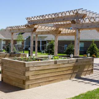 A beautifully designed outdoor garden area featuring wooden planters and a pergola, perfect for planting and relaxation.