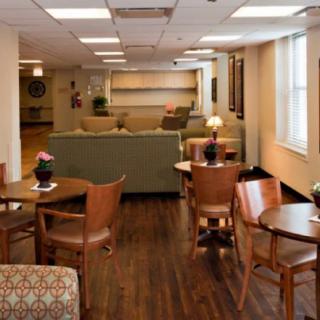 A cozy lounge area with tables and chairs, featuring comfortable seating and warm lighting.