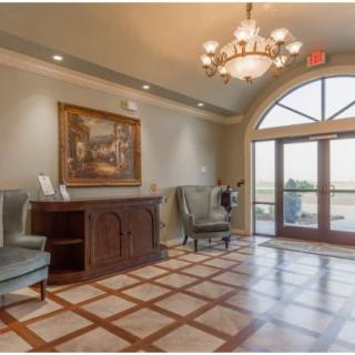 A stylish lobby featuring elegant armchairs, a chandelier, and a large window allowing natural light to fill the space.