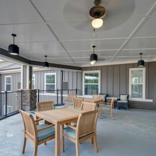 A covered patio area with wooden furniture and ceiling fans.