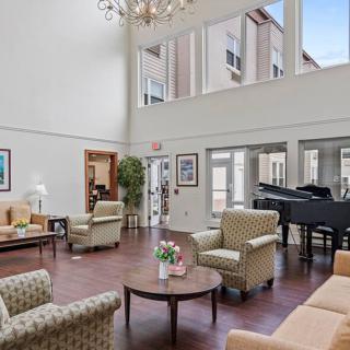A spacious and elegant living room with a grand piano, large windows, and modern furniture.