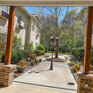 A serene garden pathway bordered by trees and plants leading to residential buildings.