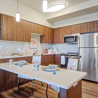 A modern kitchen with wooden cabinets, stainless steel appliances, and a dining table set for a meal.