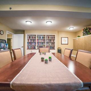 A cozy conference room with a large wooden table, surrounded by chairs and flanked by bookshelves.
