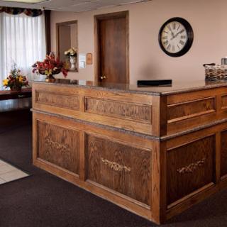 A welcoming reception area featuring a wooden front desk, decorative flowers, and a clock on the wall.