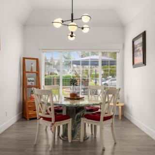 A bright and modern dining room featuring a stylish table and chairs, illuminated by an elegant chandelier, with a view of the outdoors.