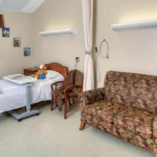 A hospital room with a patient bed and a floral-patterned sofa.