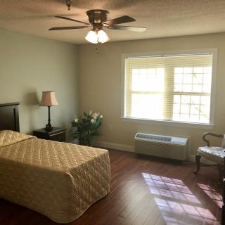 A simple, sunlit bedroom with a single bed and basic furnishings.