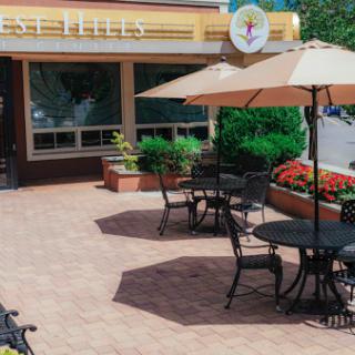 A charming outdoor seating area of a cafe featuring tables with umbrellas and vibrant flower beds.