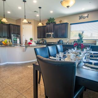 A modern dining area with a beautifully set table, adjacent to an open kitchen.