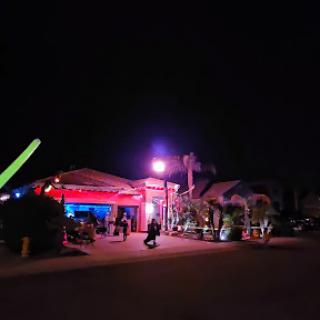 A vibrant nightlife scene with neon lights illuminating the outdoor bar.