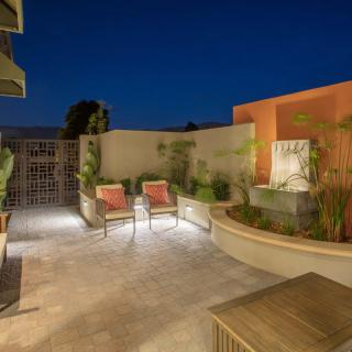 A modern patio at night featuring a stylish seating area and a small fountain, illuminated by soft outdoor lighting.