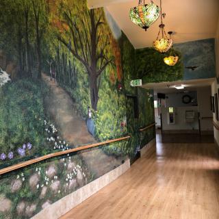A hallway with a forest-themed mural and decorative lanterns.
