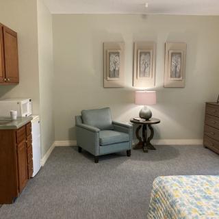 A cozy living room with an armchair, side table, lamp, and wall artwork.