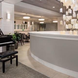 A modern hotel lobby featuring a grand piano and elegant chandeliers.