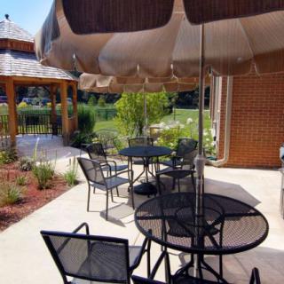 A sunny outdoor patio with tables and chairs, alongside a garden and gazebo.