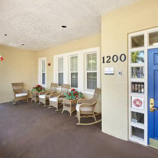 A cozy porch with wicker chairs and a blue front door, marked with the number 1200.