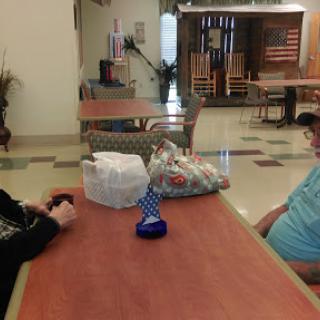 Two individuals sit at a table engaging in conversation in a communal space.