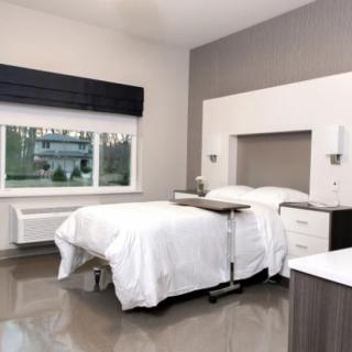 A modern, minimalist bedroom with a neatly made bed and large window.