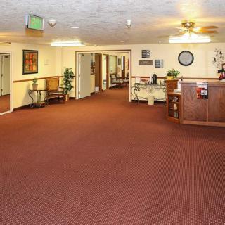 A spacious lobby with a carpeted floor, featuring a reception desk and hallway leading to various rooms.