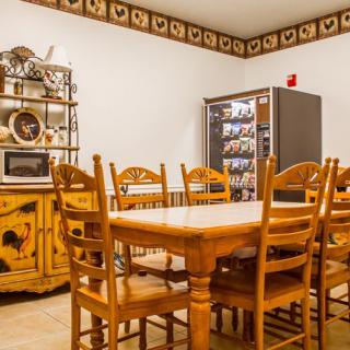 A cozy dining area featuring wooden furniture and a vending machine, complemented by country-style decor.