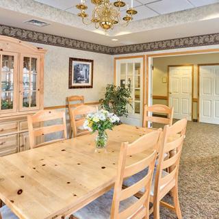 A cozy dining room with wooden furniture and a chandelier, adorned with a vase of flowers.