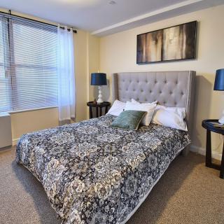 A cozy bedroom featuring a patterned bedspread, tufted headboard, and elegant nightstands with matching lamps.