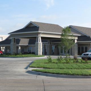 A modern office building with a driveway and parked cars.
