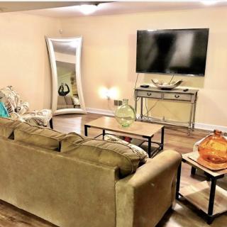 A cozy living room with a sofa, large mirror, and a wall-mounted television.